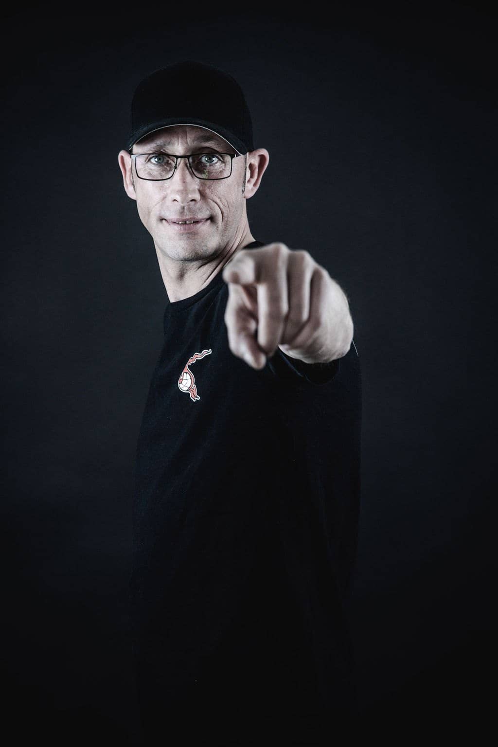 Armin Sintitsch von NOVUM mit Kappe und Brille vor dunklem Hintergrund